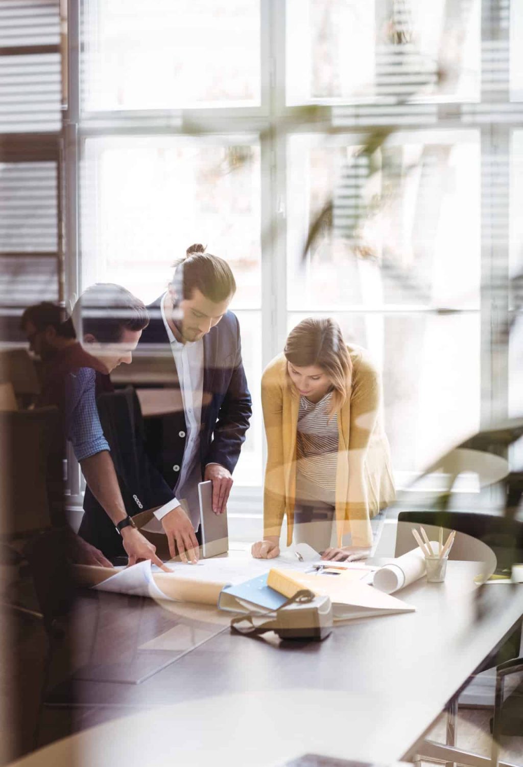 Business people with digital tablet and blueprint on table seen through glass